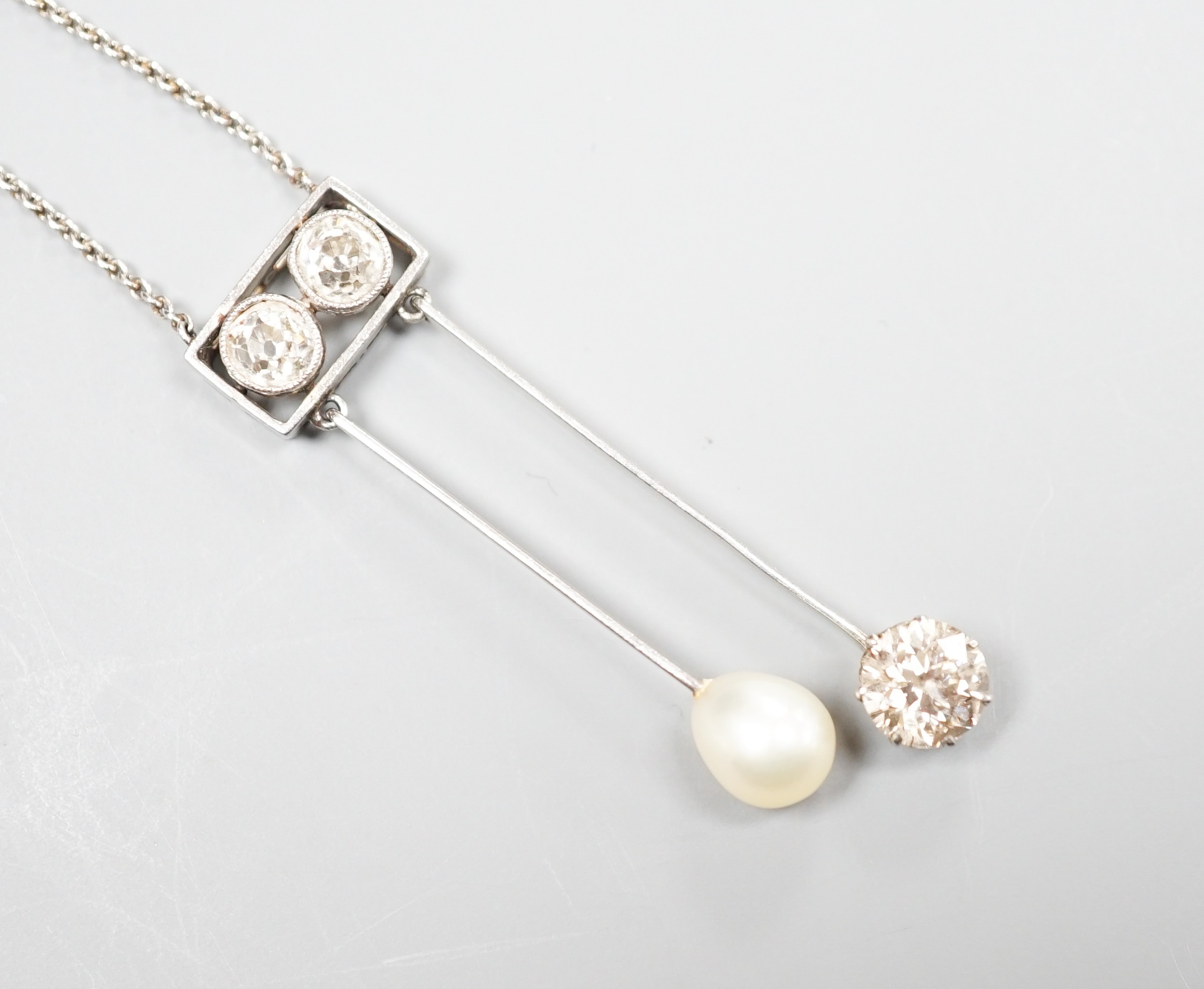 A 1940's white metal (probably platinum), three stone diamond and single stone teardrop shaped pearl set double drop pendant necklace, pendant 39mm, chain 41cm, gross weight 5.9 grams.